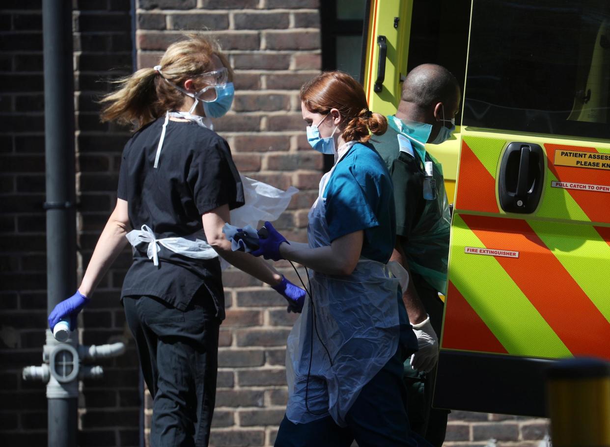 Medical staff wearing personal protective equipment (PPE) at the back of an ambulance outside Lewisham hospital: REUTERS