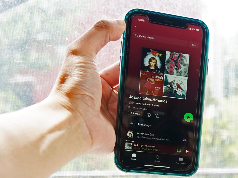 The author's hand holds a phone with a spotify playlist on the screen