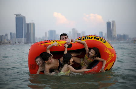 A man plays with his family at Mamzar beach in Dubai, United Arab Emirates in this October 25, 2013 file photo. REUTERS/Ahmed Jadallah/Files