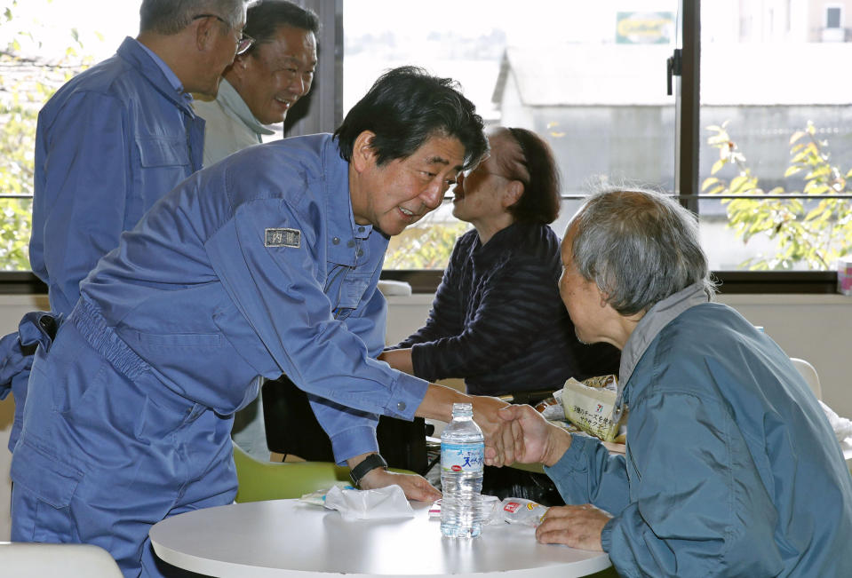 Japan's Prime Minister Shinzo Abe, front left, visits a shelter for people affected by Typhoon Hagibis, in Motomiya, Fukushima prefecture, Japan Thursday, Oct. 17, 2019. The typhoon hit Japan on Saturday with historic rainfall that caused rivers to overflow and left thousands of homes flooded, damaged or without power. (Shohei Miyano/Kyodo News via AP)