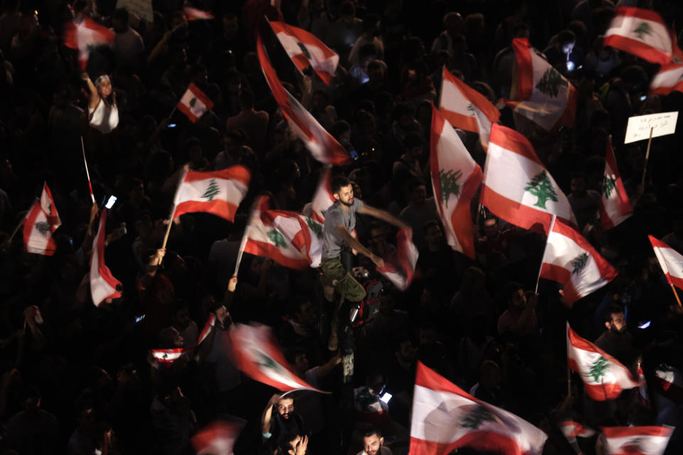 Anti-government protesters wave Lebanese flags and shout slogans against the Lebanese government during a protest in Beirut, Lebanon, Monday, Oct. 21, 2019. Lebanon's Cabinet approved Monday sweeping reforms that it hopes will appease thousands of people who have been protesting for five days, calling on Prime Minister Saad Hariri's government to resign. (AP Photo/Hassan Ammar)