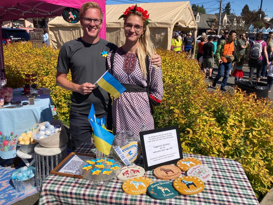 Natalia Burkut, from Ukraine, right, and her friend John Larson of Poulsbo, left, sell handcrafted door signs at Viking Fest in Poulsbo to support Burkut's relatives and friends who are still in Ukraine.