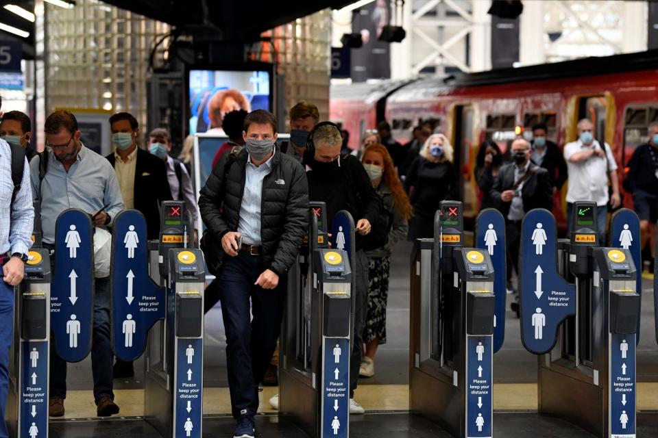 People wearing protective face masks are seen arriving at Waterloo station, the busiest train station in the UK (REUTERS)