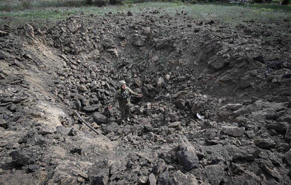 A Ukrainian serviceman stands in a crater after a recent Russian attack on a village in the Mykolaiv region on Sept. 24, 2022, amid the Russian invasion of Ukraine.