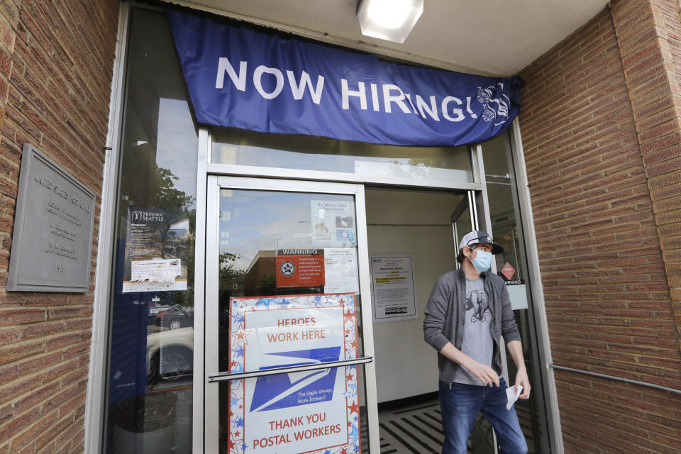 FILE - In this Thursday, June 4, 2020 file photo, a customer walks out of a U.S. Post Office branch and under a banner advertising a job opening, in Seattle. The job market took a big step toward healing in May 2020, though plenty of damage remains, as a record level of hiring followed record layoffs in March and April. The Labor Department reported Tuesday, July 7, 2020 that the number of available jobs rose sharply as well, but remained far below pre-pandemic levels. (AP Photo/Elaine Thompson, File)