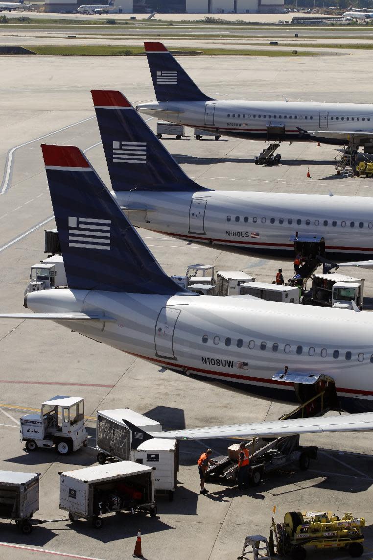 In this Thursday, Sept. 27, 2012, photo, US Airways jets are parked at their gates at the Charlotte/Douglas International airport in Charlotte, N.C. Patched together from several scrappy regional carriers on the brink of bankruptcy, US Airways has often been ridiculed within the aviation industry and remains a perennial afterthought among travelers. But it hopes to shed that image by merging with the larger American Airlines, in a deal which will catapult the two to the top of the industry. (AP Photo/Chuck Burton