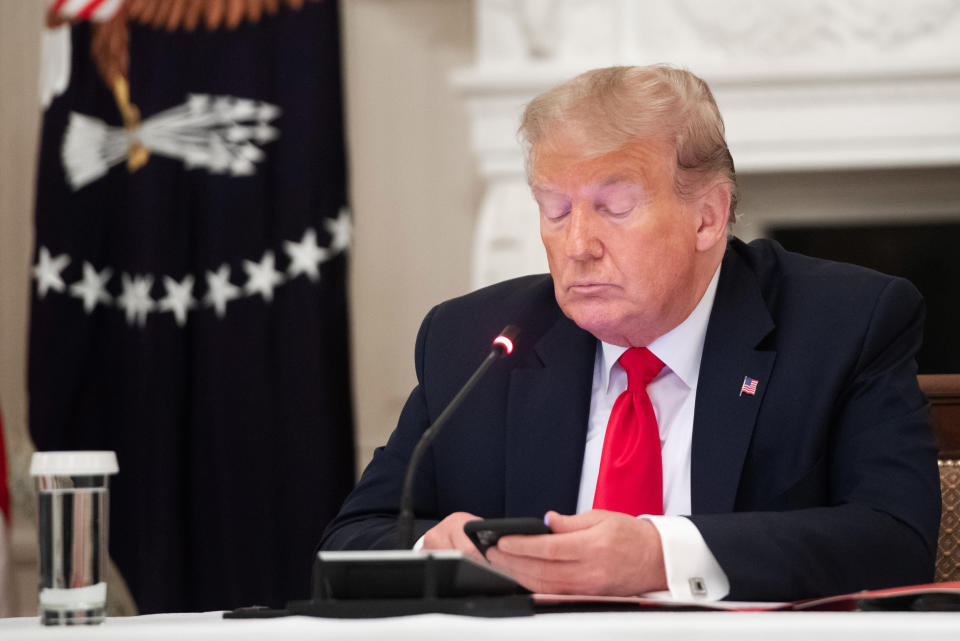 President Donald Trump uses his cellphone in the State Dining Room of the White House in Washington, D.C. (Saul Loeb / AFP via Getty Images file)