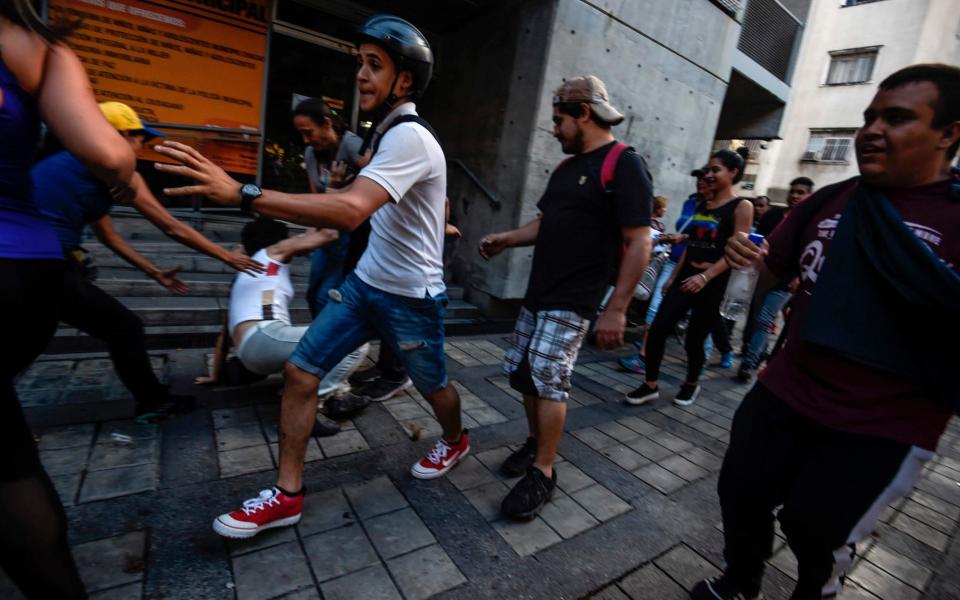 Anti-government activists scatter upon being charged by riot police during a protest  - Credit: JUAN BARRETO/AFP/Getty Images