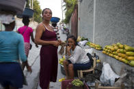 In this Nov. 27, 2019 photo, Wadlande Pierre, right, talks on her mobile phone as she helps her mother, Vanlancia Julien, center, at their fruit and vegetable stand on a sidewalk in Delmas, a district of in Port-au-Prince, Haiti. Pierre, 23, said she temporarily moved in with her aunt in the southwest town of Les Cayes to escape the violent protests in Port-au-Prince. However, she had to move back to the capital because there was no gas, power or water in Les Cayes, and food was becoming scarce. (AP Photo/Dieu Nalio Chery)