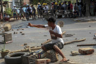 An anti-coup protester uses a sling-shot and against advancing riot policemen in Mandalay, Myanmar, Tuesday, March 2, 2021. Demonstrators in Myanmar took to the streets again on Tuesday to protest last month’s seizure of power by the military, as foreign ministers from Southeast Asian countries met to discuss the political crisis. Police in Yangon, Myanmar’s biggest city, used tear gas and rubber bullets against the protesters. (AP Photo)