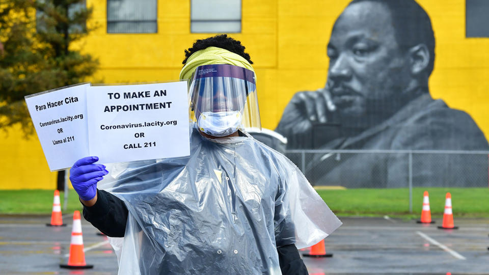 Dressed in protective gear, university student working on her master's degree Jacquelyn Augustine displays information for arranging COVID-19 testing in Los Angeles on April 8, 2020. (Frederic J. BROWN / AFP) 