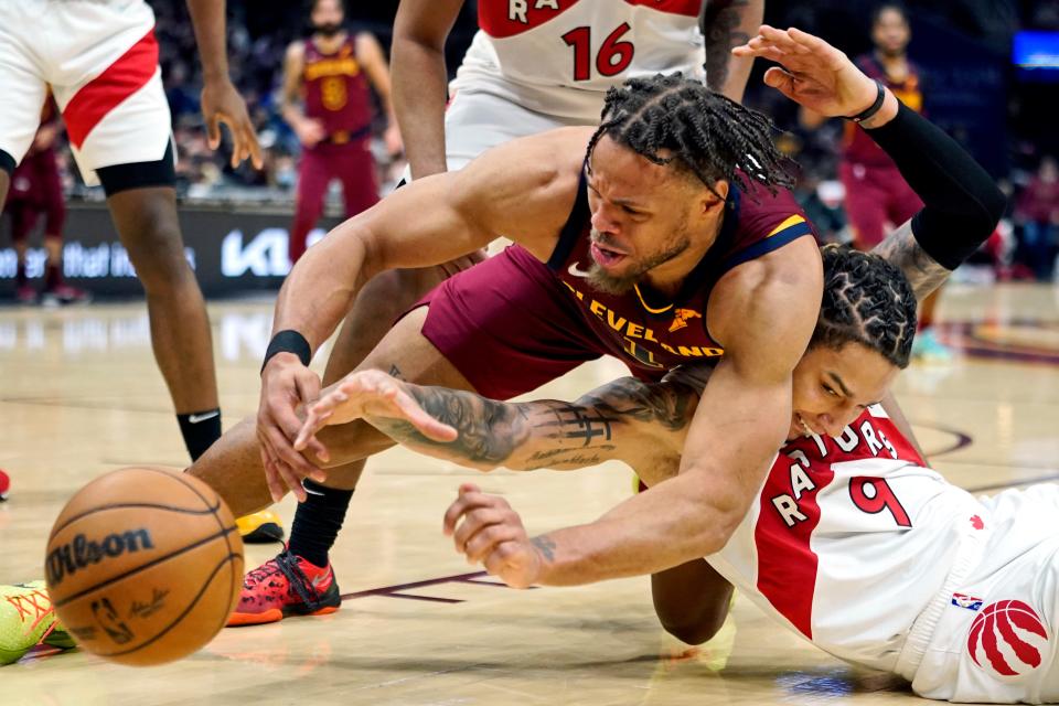 Cleveland Cavaliers' Justin Anderson, left, and Toronto Raptors' D.J. Wilson battle for a loose ball in the first half of an NBA basketball game, Sunday, Dec. 26, 2021, in Cleveland. (AP Photo/Tony Dejak)