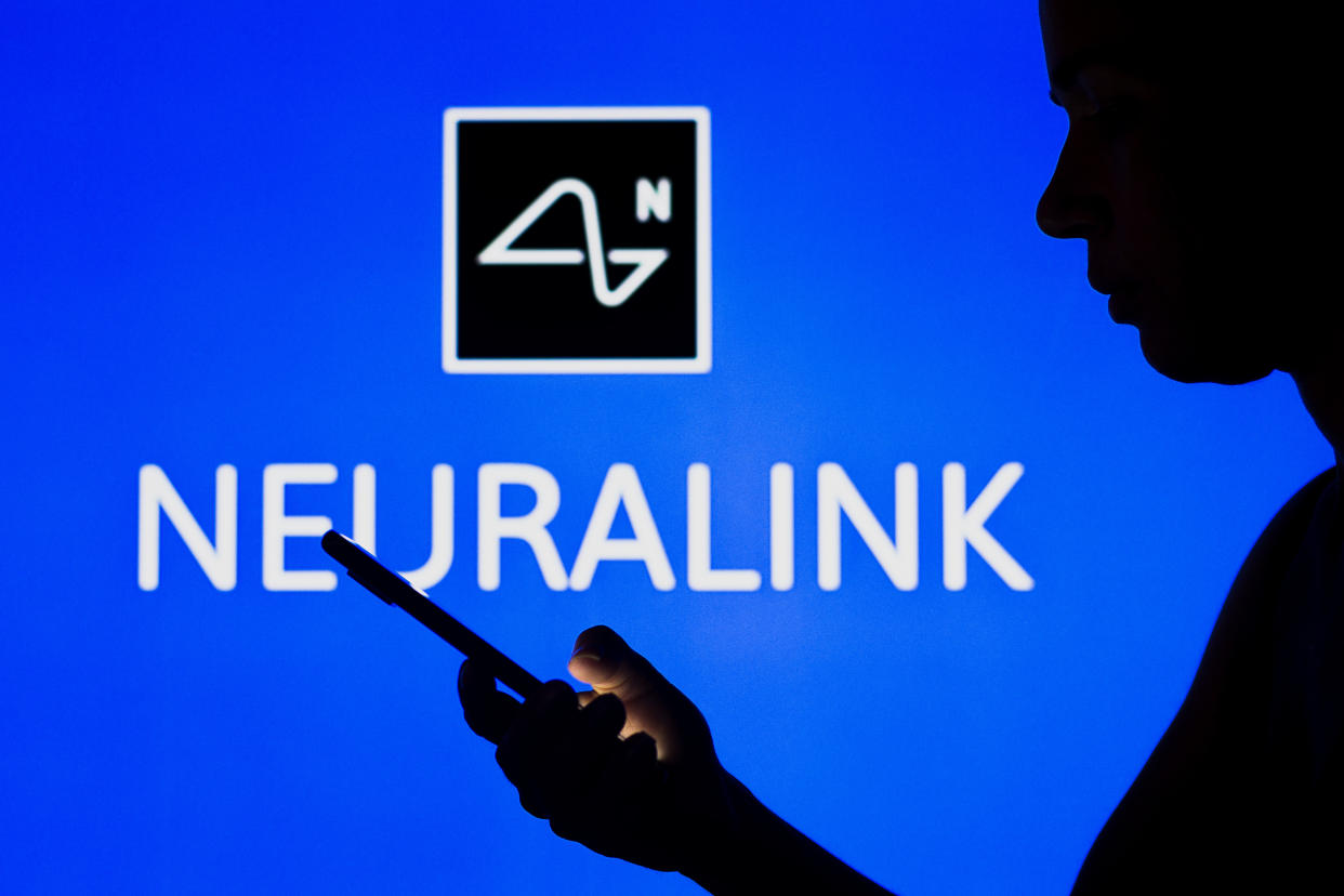 BRAZIL - 2022/05/02: In this photo illustration, the Neuralink logo is seen in the background of a silhouetted woman holding a mobile phone. (Photo Illustration by Rafael Henrique/SOPA Images/LightRocket via Getty Images)
