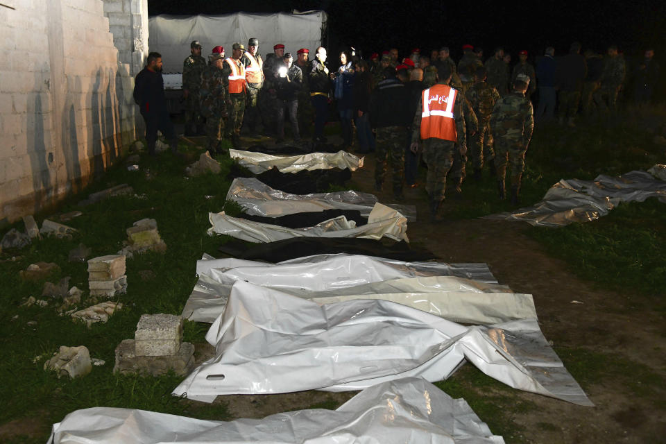 In this photo released Monday, Feb. 17, 2020 by the Syrian official news agency SANA, Syrian security forces check human remains at the site of a mass grave believed to contain the bodies of civilians and troops in Douma, near the Syrian capital Damascus. Syrian state media reported that authorities have exhumed nearly 70 bodies of civilians and soldiers including a woman, most of them shot at close range. (SANA via AP)