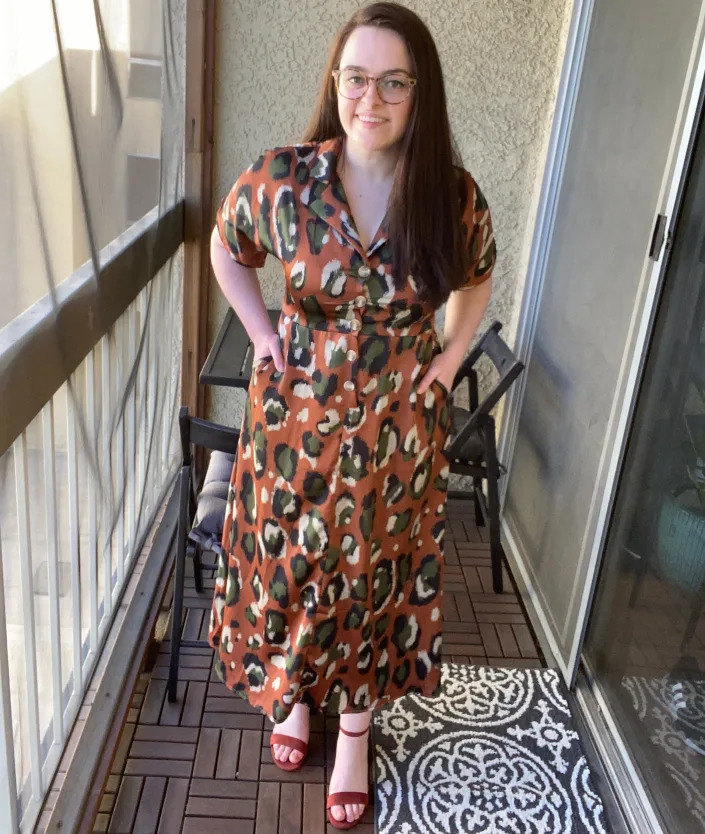 The writer on a balcony wearing Patterned button-down dress, rust-colored heels.