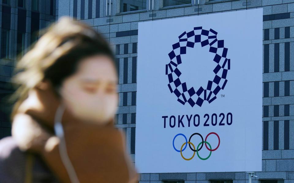 A woman wearing a protective mask to help curb the spread of the coronavirus walks near a banner of the Tokyo 2020 Olympics in Tokyo Tuesday, Jan. 19, 2021. The Japanese capital confirmed more than 1200 new coronavirus cases on Tuesday - AP/Eugene Hoshiko 