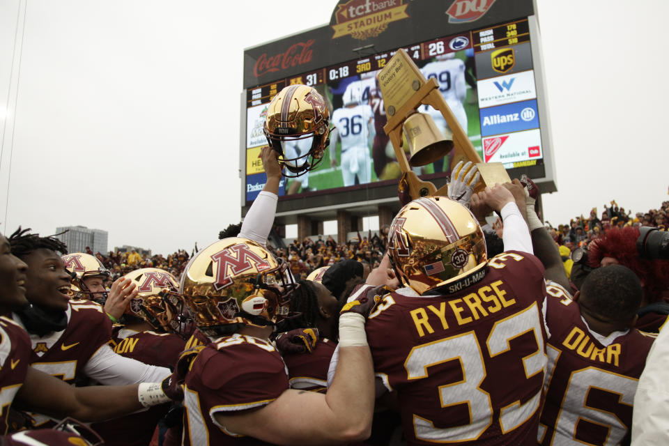 FILE - In this Nov. 9, 2019, file photo, Minnesota football players hold up the Governor's Victory Bell after winning 31-26 against Penn State during an NCAA college football game in Minneapolis. Big Ten is going to give fall football a shot after all. Less than five weeks after pushing football and other fall sports to spring in the name of player safety during the pandemic, the conference changed course Wednesday, Sept. 16, 2020, and said it plans to begin its season the weekend of Oct. 23-24. (AP Photo/Stacy Bengs, File)