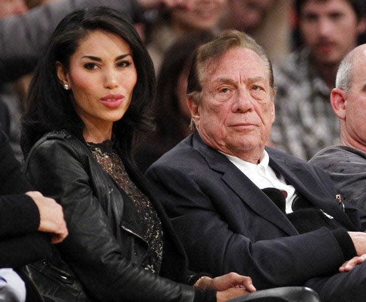 Los Angeles Clippers owner Donald Sterling sits with V. Stiviano during a preseason game in Los Angeles on Dec. 12, 2010. Sterling was banned for life from the Clippers organization over racist comments.