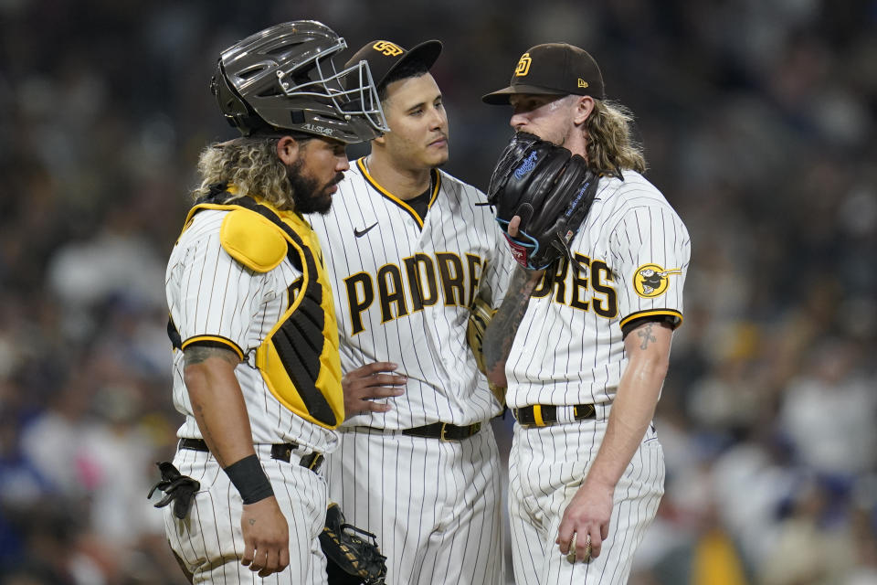 San Diego Padres relief pitcher Josh Hader, right, talks on the mound with third baseman Manny Machado, center, and catcher Jorge Alfaro after Los Angeles Dodgers' Trea Turner scored the tying run on a passed ball during the ninth inning of a baseball game Tuesday, Sept. 27, 2022, in San Diego. (AP Photo/Gregory Bull)