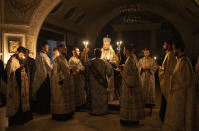 Metropolitan Oleksandr delivers a religious service with clerics inside the Transfiguration of Jesus Orthodox Cathedral during blackout caused by recent Russian rocket attacks, in Kyiv, Ukraine, Saturday, Dec. 3, 2022. A top Orthodox priest in Ukraine's capital says he supports the efforts of President Volodymyr Zelenskyy's government and counter-intelligence agency to end Russian spying and meddling in Ukrainian politics through a Moscow-affiliated church. (AP Photo/Efrem Lukatsky)