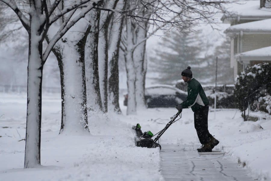 A man cleans the snow off a walkway in front of a house in Wheeling, Ill., Friday, Jan. 12, 2024. (AP Photo/Nam Y. Huh)