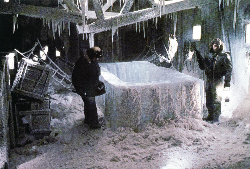 A large frozen container in an abandoned science station and two men investigating it