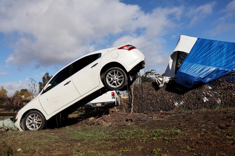 SAN DIEGO, CALIFORNIA - JANUARY 23: A vehicle moved by flooding remains lodged on a fence the day after an explosive rainstorm deluged areas of San Diego County on January 23, 2024 in San Diego, California. The intense rains forced dozens of rescues while flooding roadways and homes and knocking out electricity for thousands of residents.