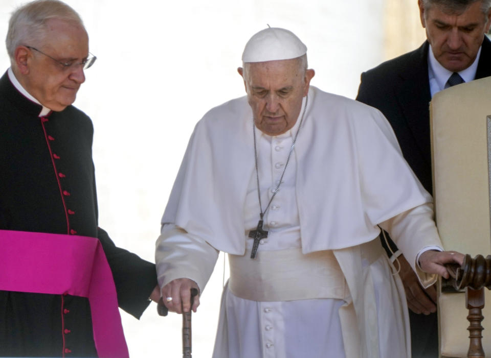 FILE - Pope Francis is helped by his aide Monsignor Leonardo Sapienza, left, as he walks with a cane to his weekly general audience in St. Peter's Square at The Vatican on June 1, 2022. Pope Francis added fuel to rumors about the future of his pontificate on Saturday by announcing he would visit the central Italian city of L'Aquila in August for a feast initiated by Pope Celestine V, one of the few pontiffs who resigned before Pope Benedict XVI stepped down in 2013. (AP Photo/Gregorio Borgia, File)