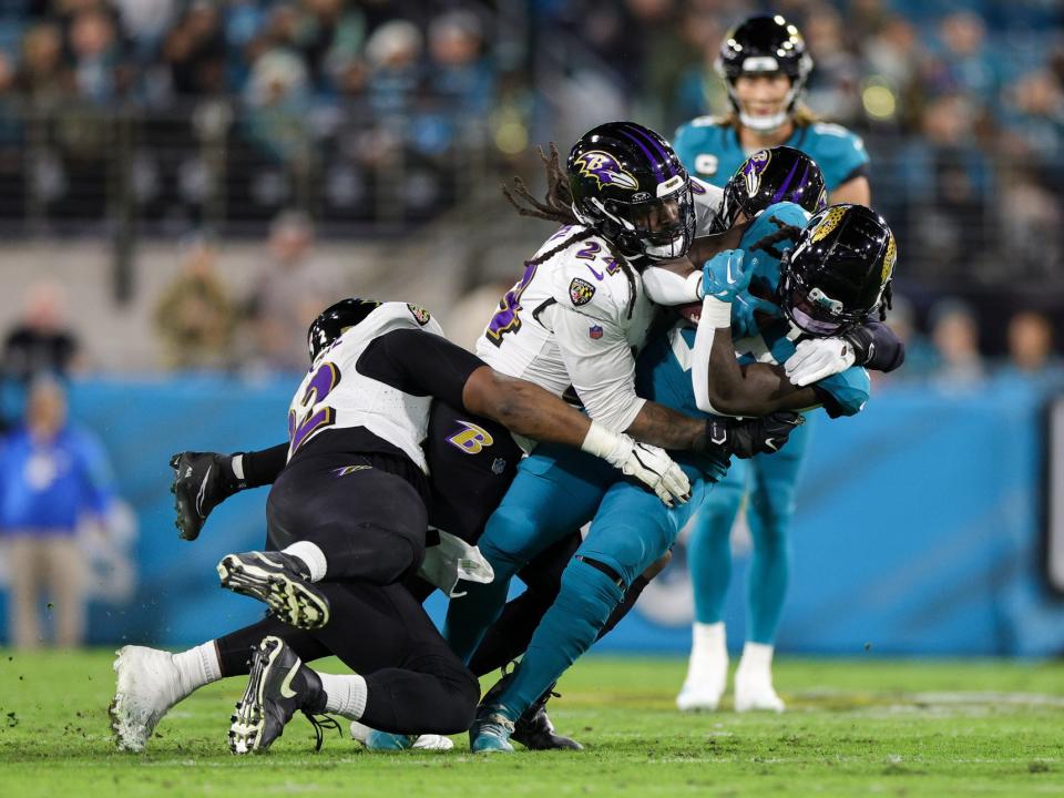 Dec 17, 2023; Jacksonville, Florida, USA; Jacksonville Jaguars running back D’Ernest Johnson (25) is tackled by Baltimore Ravens linebacker Jadeveon Clowney (24) in the second quarter at EverBank Stadium. Mandatory Credit: Nathan Ray Seebeck-USA TODAY Sports