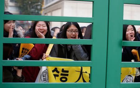 Students from a high school cheer for their seniors in front of a gate at the examination hall before they take the annual college entrance examinations in Seoul, South Korea, November 17, 2016. REUTERS/Kim Kyung-Hoon