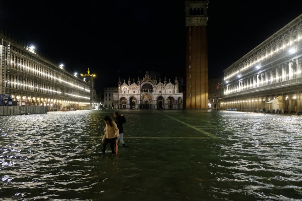 People walk in a flooded St.Mark's Square during a period of seasonal high water in Venice, Italy November 12, 2019. REUTERS/Manuel Silvestri