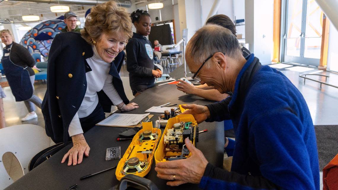 Ramona Higer, left, watches as Andy Huang takes apart her boombox to fix the radio function at Thursday’s “repair cafe.”