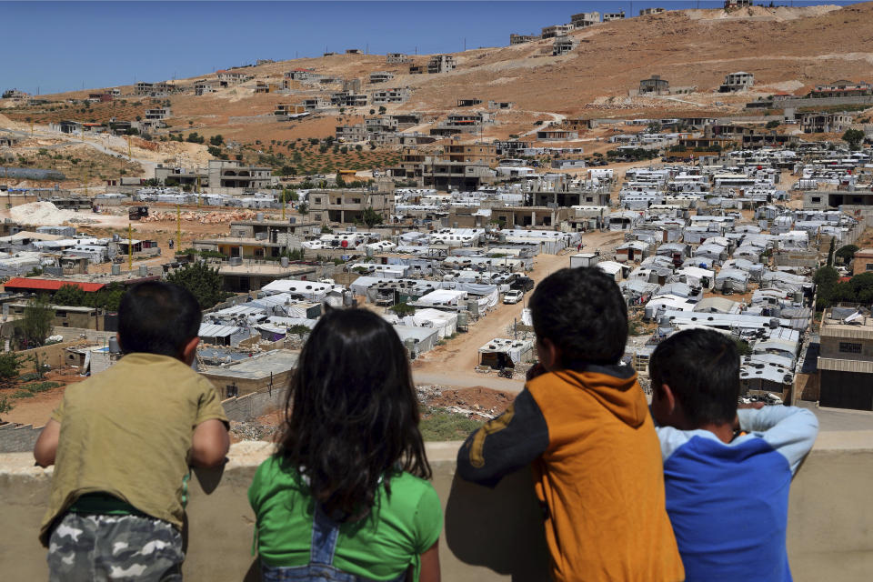 In this Sunday, June 16, 2019 photo, Lebanese children look from the rooftop of their home at a Syrian camp in the eastern Lebanese border town of Arsal, Lebanon. Authorities in Lebanon are waging their most aggressive campaign yet against Syrian refugees, making heated calls for them to go back to their country and taking action to ensure they can’t put down roots. They are shutting down shops where Syrians work without permits and ordering the demolition of anything in their squalid camps that could be a permanent home. (AP Photo/Bilal Hussein)