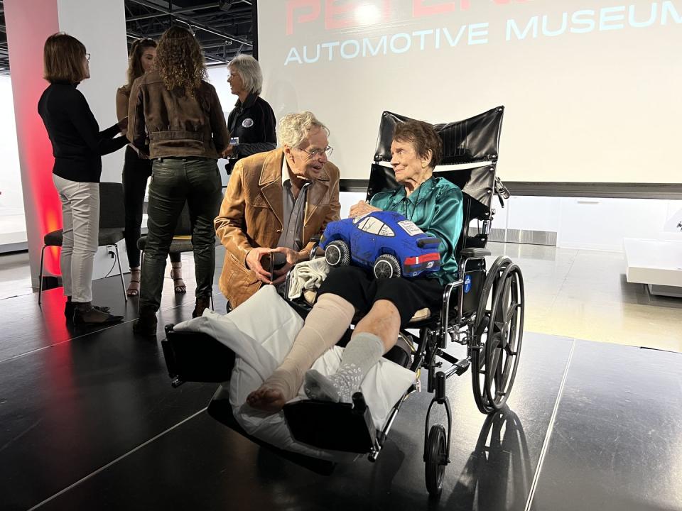 paula murphy seated in a wheelchair speaks with a friend at the petersen automotive museum