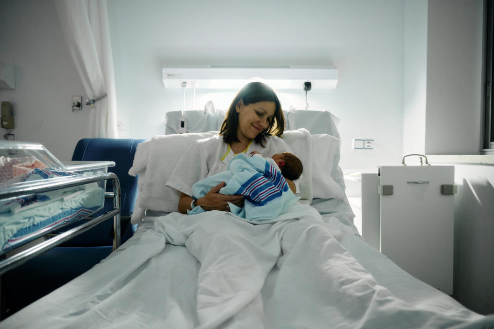 a smiling mother after breastfeeding her newborn in a hospital bed