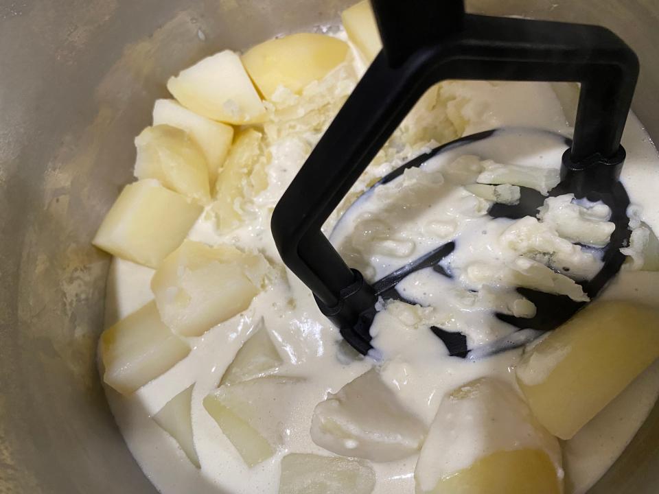 mashing potatoes in a pot on the stove