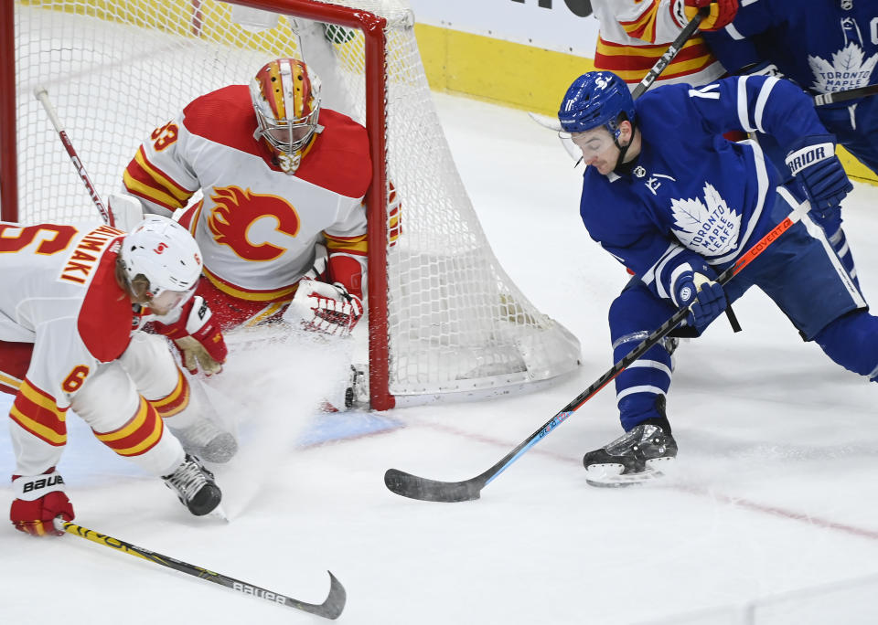 Toronto Maple Leafs forward Zach Hyman (11) shoots on Calgary Flames goaltender David Rittich (33) as Flames defenseman Juuso Valimaki (6) keeps close during second-period NHL hockey game action in Toronto, Saturday, March 20, 2021. (Nathan Denette/The Canadian Press via AP)