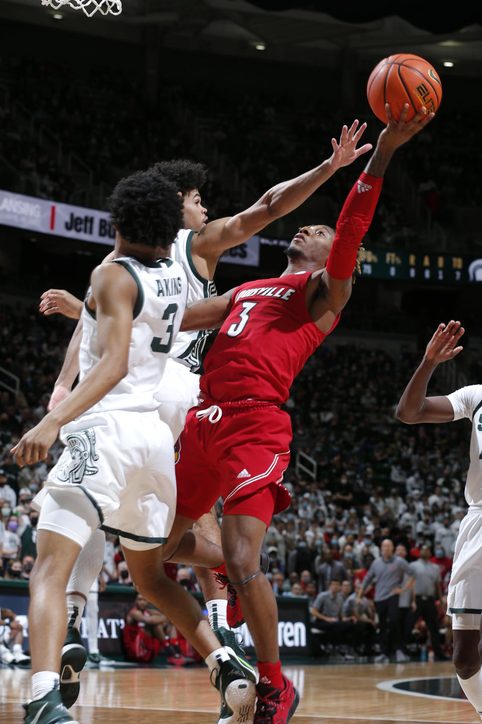 Louisville's El Ellis, right, shoots against Michigan State's Malik Hall, left rear, and Jaden Akins (3) during the first half of an NCAA college basketball game Wednesday, Dec. 1, 2021, in East Lansing, Mich. (AP Photo/Al Goldis)