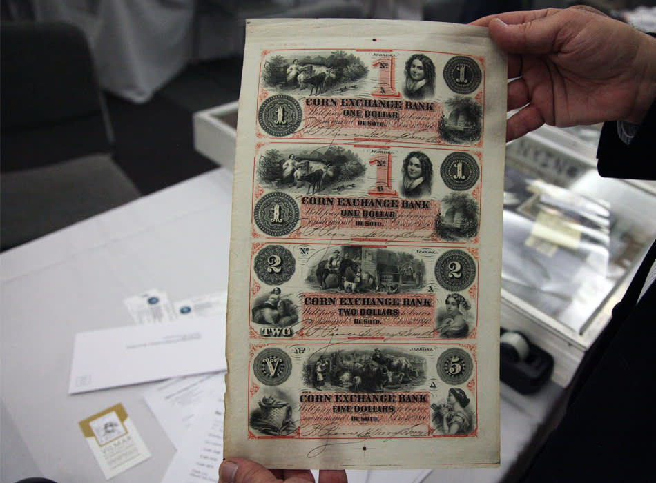 Dr. Robert Schwartz holds a sheet of banknotes issued by the Corn Exchange Bank of Nebraska.