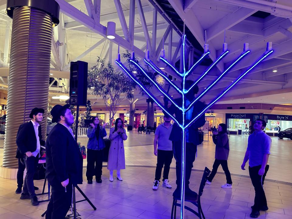 The “Roving Rabbis” light the menorah set up at Center Court of Westgate Mall in Amarillo on Tuesday during the sixth night of the eight-day Festival of Lights.