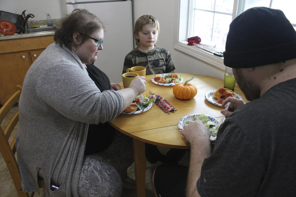 Airis Messick, left, and Brian Messick, right, eat lunch with this 9-year-old son, Jayden, at their apartment in Anchorage, Alaska, on Wednesday, Nov. 11, 2020. Messick and her husband have had to turn to food banks after both lost their jobs in the economic downturn caused by the coronavirus pandemic. Airris, who just turned 30, found work in August, ironically, at the state unemployment office. “I hear people’s stories all day,” she says. “I listen to moms cry about not having money to take care of their kids. My heart aches for the people who get denied.” (AP Photo/Mark Thiessen)