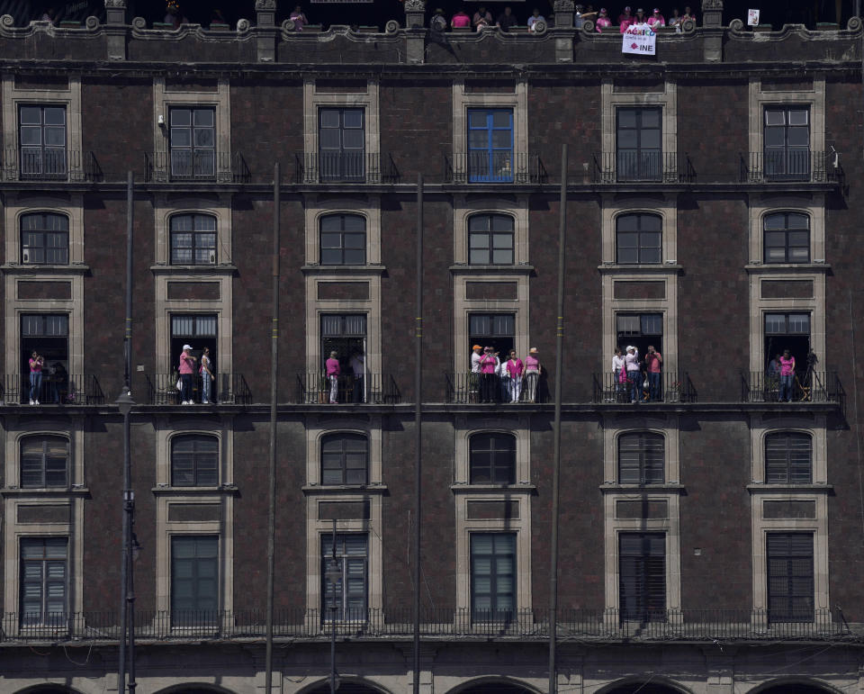 Anti-government demonstrators look from the balconies of a building adjacent to Mexico City's main square, The Zocalo, during a protest against Mexican President Andres Manuel Lopez Obrador, and his recent reforms to the country's electoral law that they say threaten democracy, Sunday, Feb. 26, 2023. (AP Photo/Fernando Llano)