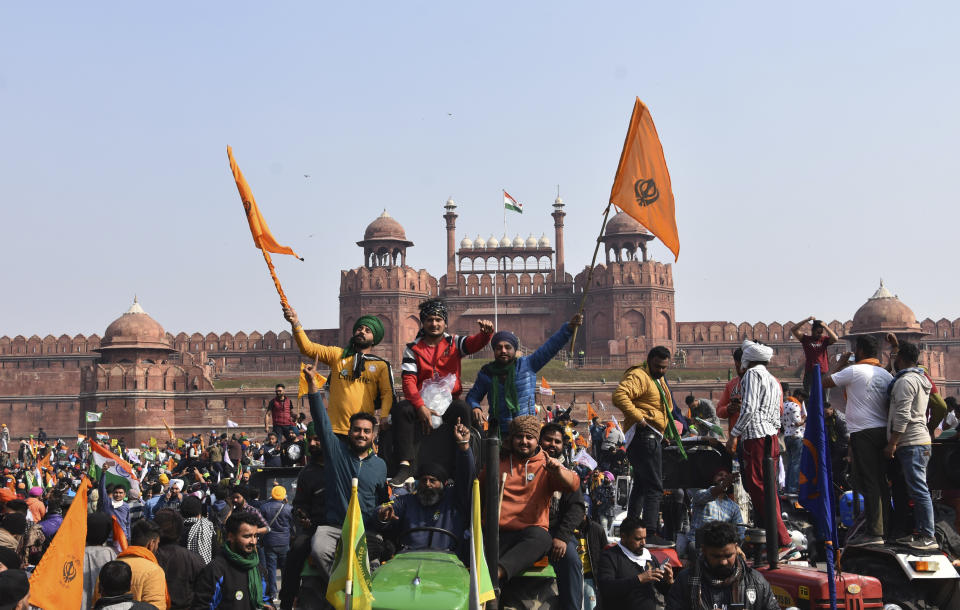 Sikhs wave the Nishan Sahib, a Sikh religious flag, as they arrive at the historic Red Fort monument in New Delhi, India, Tuesday, Jan. 26, 2021. Tens of thousands of protesting farmers drove long lines of tractors into India's capital on Tuesday, breaking through police barricades, defying tear gas and storming the historic Red Fort as the nation celebrated Republic Day. (AP Photo/Dinesh Joshi)