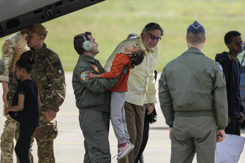 A member of the Greek airforce holds a child as evacuees from Sudan disembark a military plane at Tanagra air base, north of Athens on Wednesday, April 26, 2023. Sixteen Greeks and one Cypriot arrived in Greece after being evacuated from Sudan. (AP Photo/Thanassis Stavrakis)