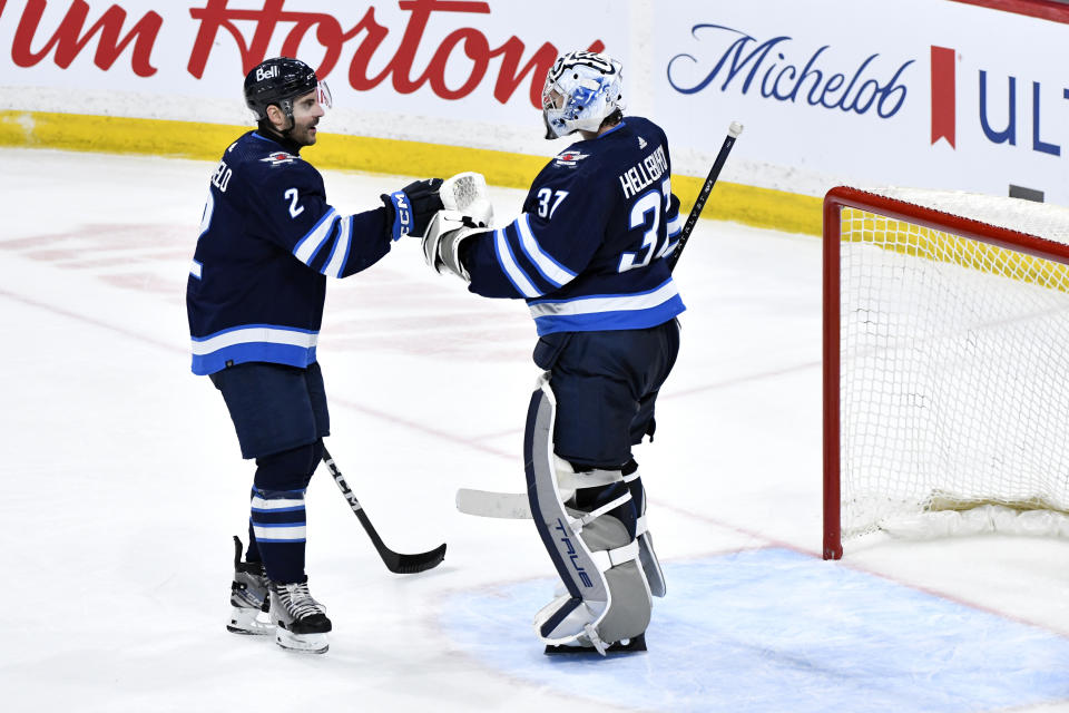 Winnipeg Jets' goaltender Connor Hellebuyck (37) celebrates the win over the Seattle Kraken with Dylan DeMelo (2) after an NHL hockey game in Winnipeg, Manitoba on Tuesday April 16, 2024. (Fred Greenslade/The Canadian Press via AP)