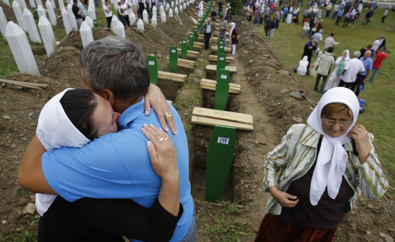 A Bosnian woman is comforted by family members during a funeral ceremony at the memorial center in Potocari