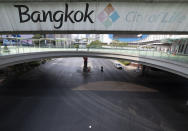 A motorcycle and car stop at the almost deserted intersection in Bangkok, Thailand, Thursday, April 2, 2020. A month long state of emergency has been enforced in Thailand to allow its government to impose stricter measures to control the coronavirus that has infected hundreds of people in the Southeast Asian country. (AP Photo/Sakchai Lalit)
