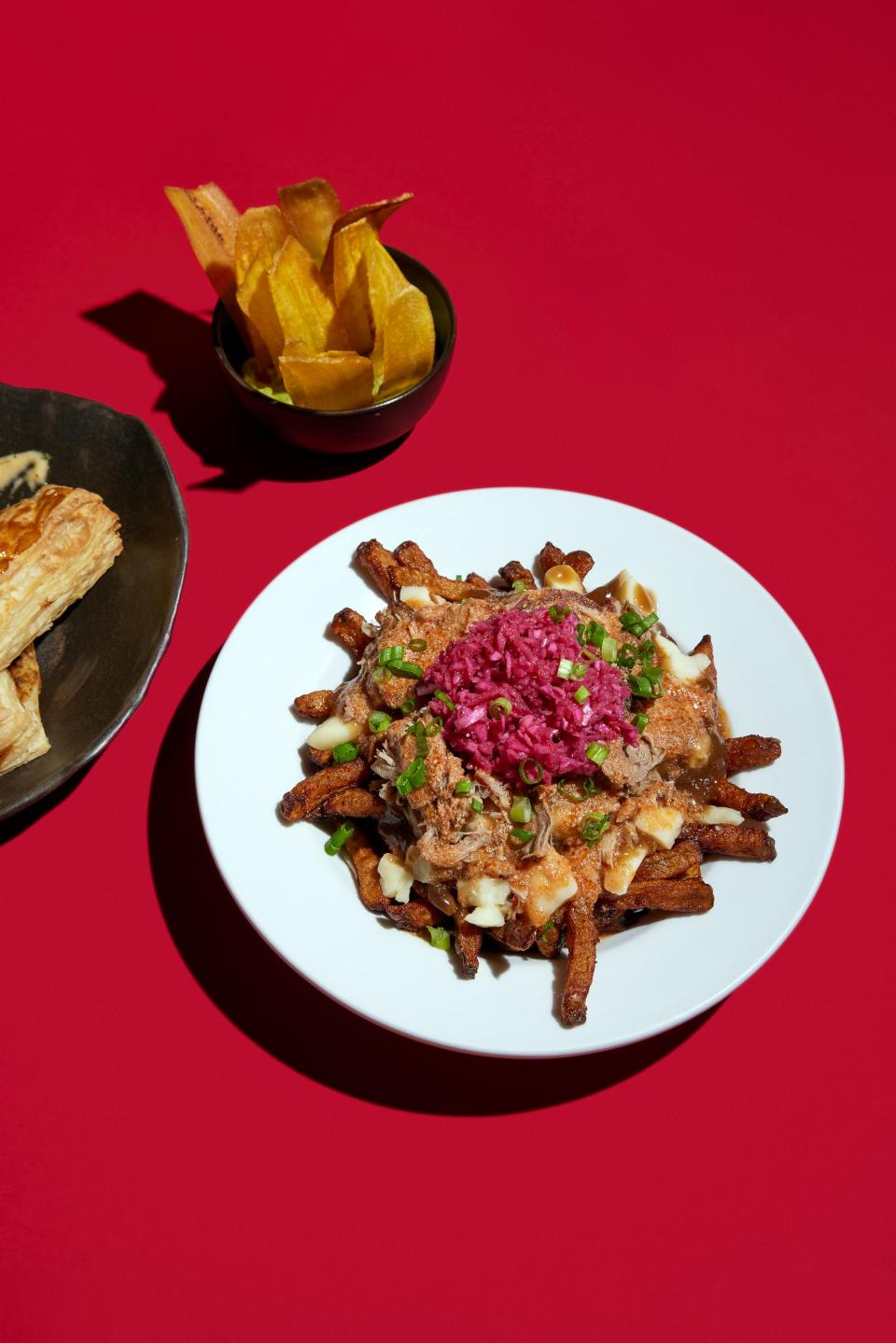 Poutine at Pikliz with pieces of pulled pork, Creole spices and pikliz with a side of Haitian patty, crispy plantains with guacamole.