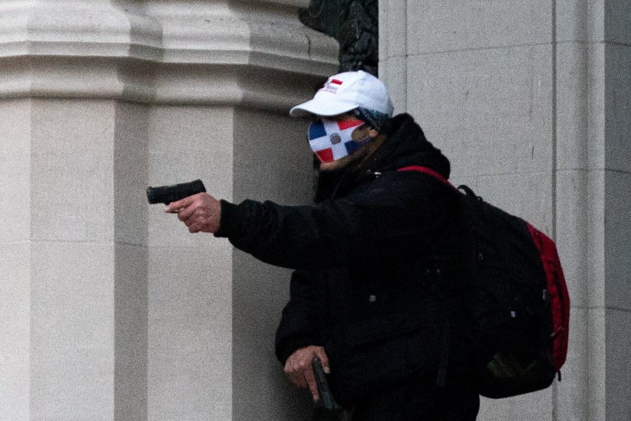 A man wearing a protective mask points his guns outside the Cathedral Church of St. John the Divine in the Manhattan borough of New York City on December 13, 2020. (Photo: Jeenah Moon / Reuters)