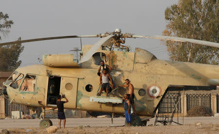 People take a picture on a damaged helicopter in Deir al-Zor airport, Syria September 20, 2017. Picture taken September 20, 2017. REUTERS/Omar Sanadiki